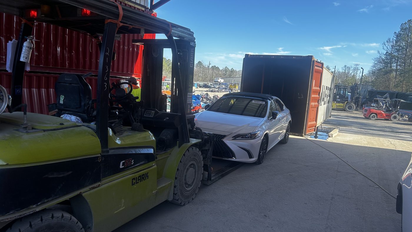Sedan being loaded into a Maersk container by forklift