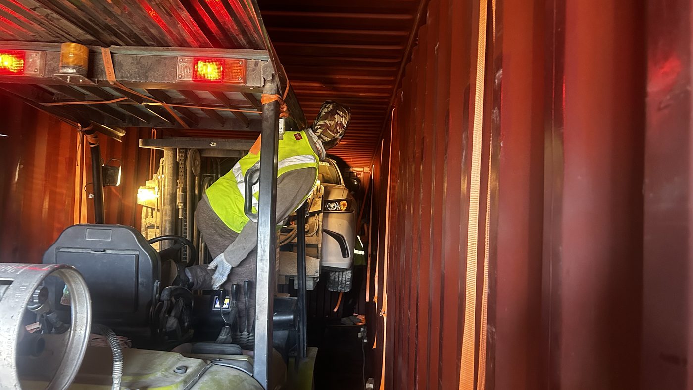 Forklift operator securing a vehicle inside a shipping container