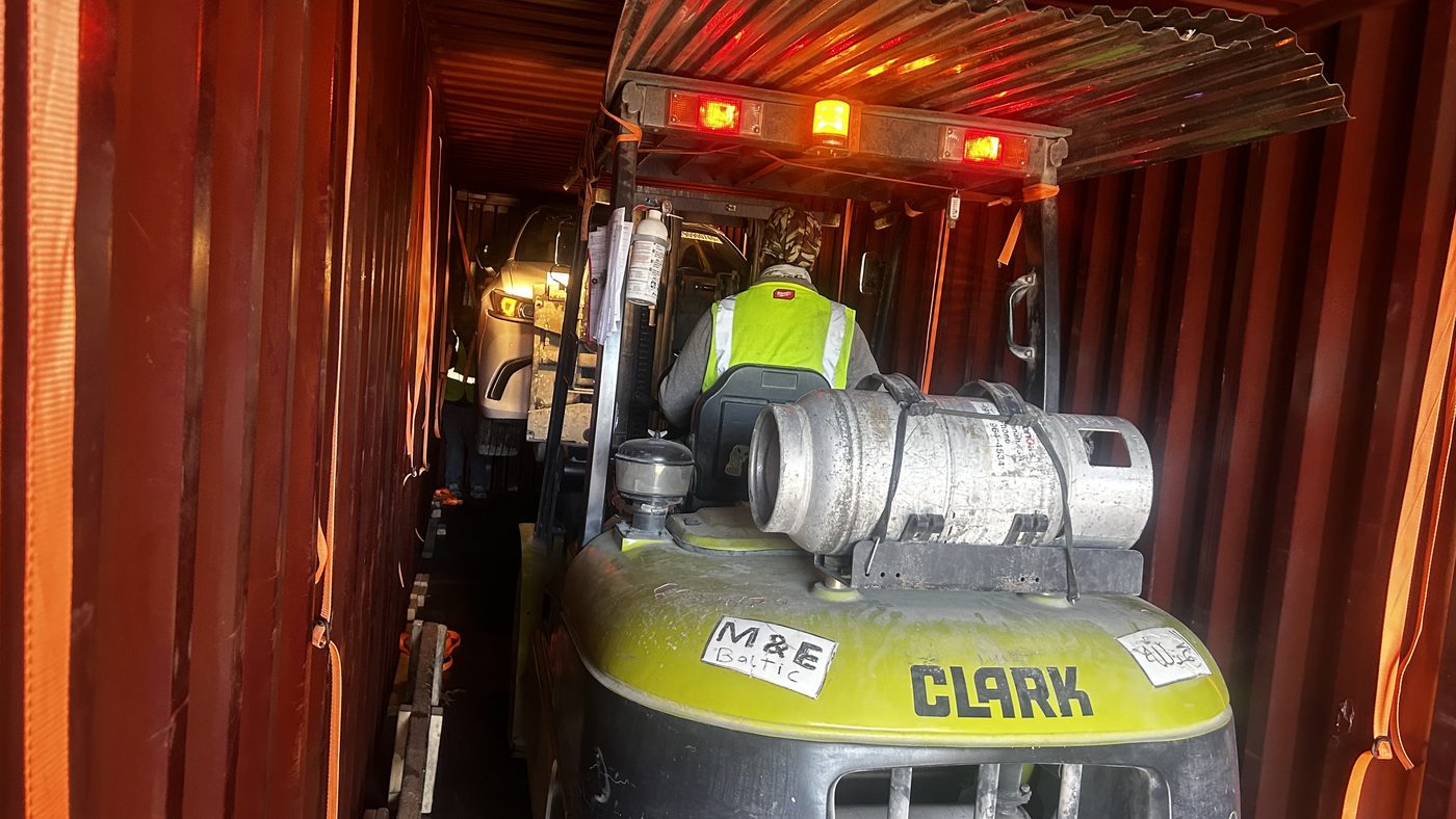 Forklift working a vehicle into a container at the warehouse